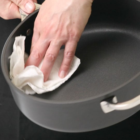 wiping the inside of a pan with a paper towel
