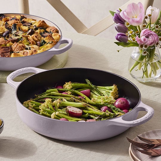 vegetables in a round shallow roasting pan with loop handles
