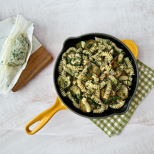 rotini in a skillet coated with herbs