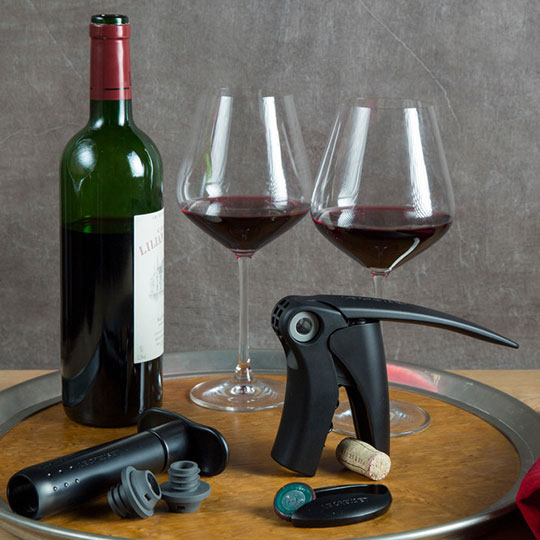 wine glasses, lever corskscrew and wine pump with stoppers alongside a bottle of red wine