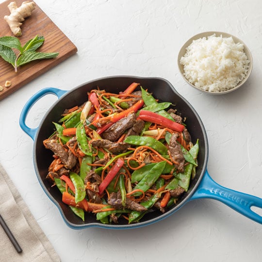 beef and asian veggies in a blue skillet