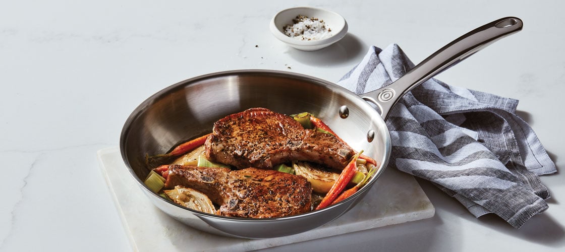 browned pork chops in a stainless skillet