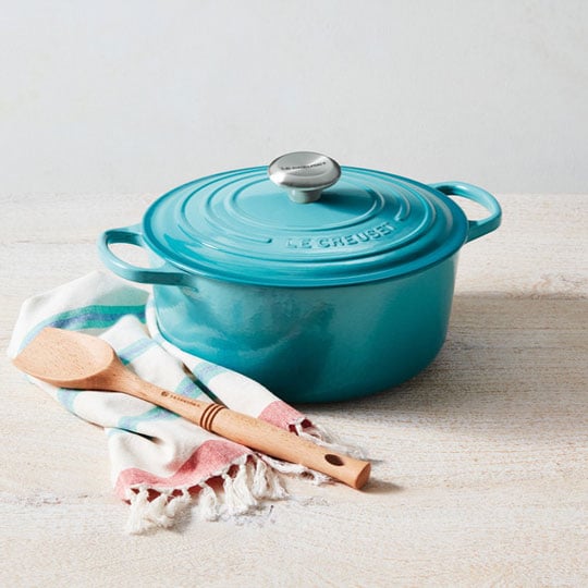 Caribbean Blue Dutch Oven next to a towel and wooden spoon