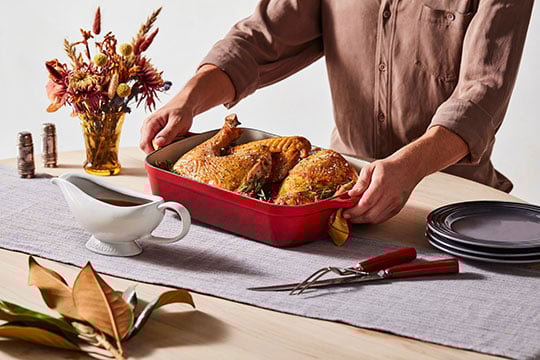 person placing roasted turkey on a table