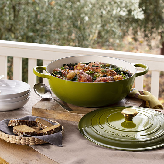 an olive green dutch oven used to serve food on the porch
