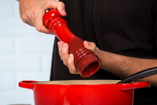 man using mill to grind salt into pot