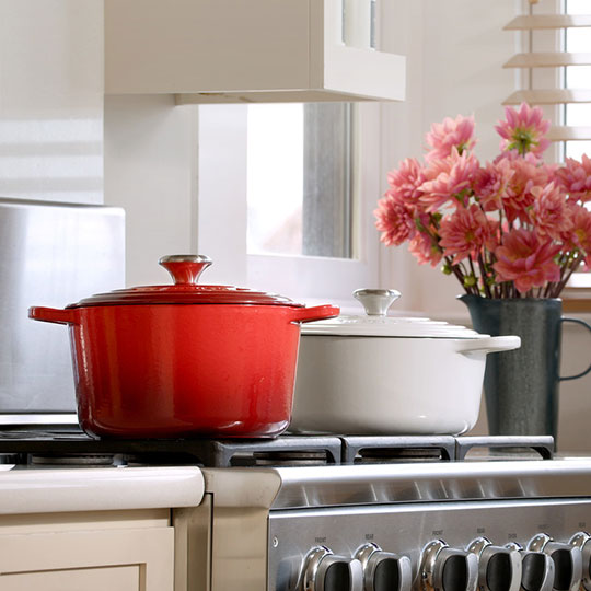 deep oven next to a standard dutch oven on a stovetop showing height difference