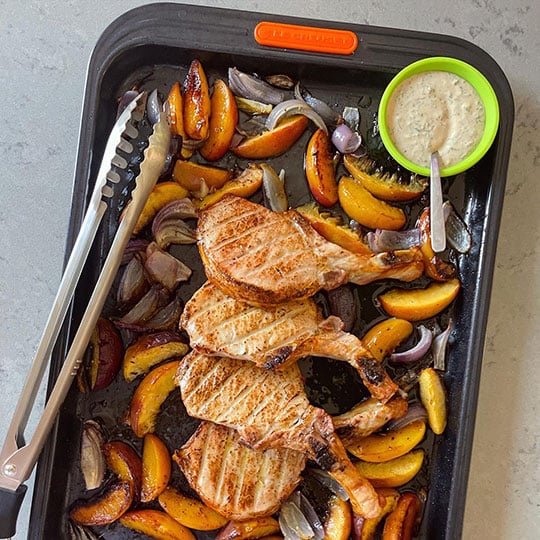 pork chops and veggies browned on a sheet pan