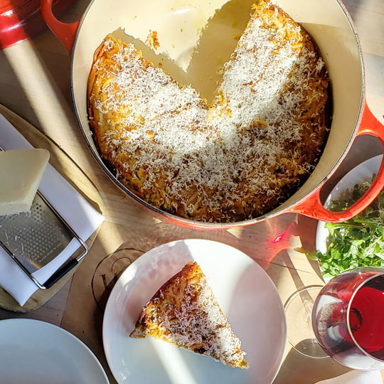 pie made of spaghetti topped with cheese in a cast iron braiser