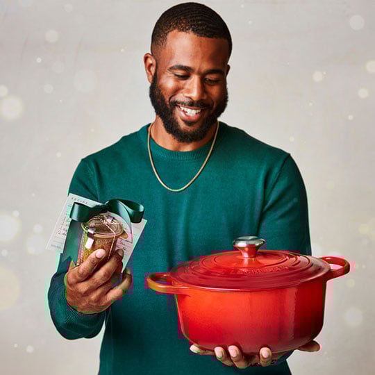 man holds dutch oven and container of spice rub wrapped in ribbons
