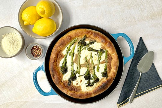 deep dish pizza topped with greens