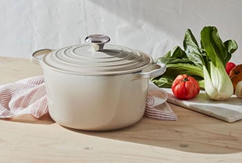 deep dutch oven next to lots of fresh veggies