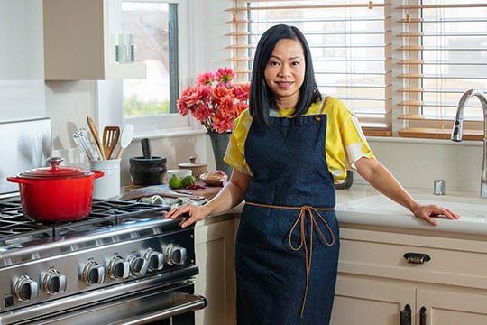 Chef Pim Techamuanvivit in her kitchen with a deep dutch oven in cerise