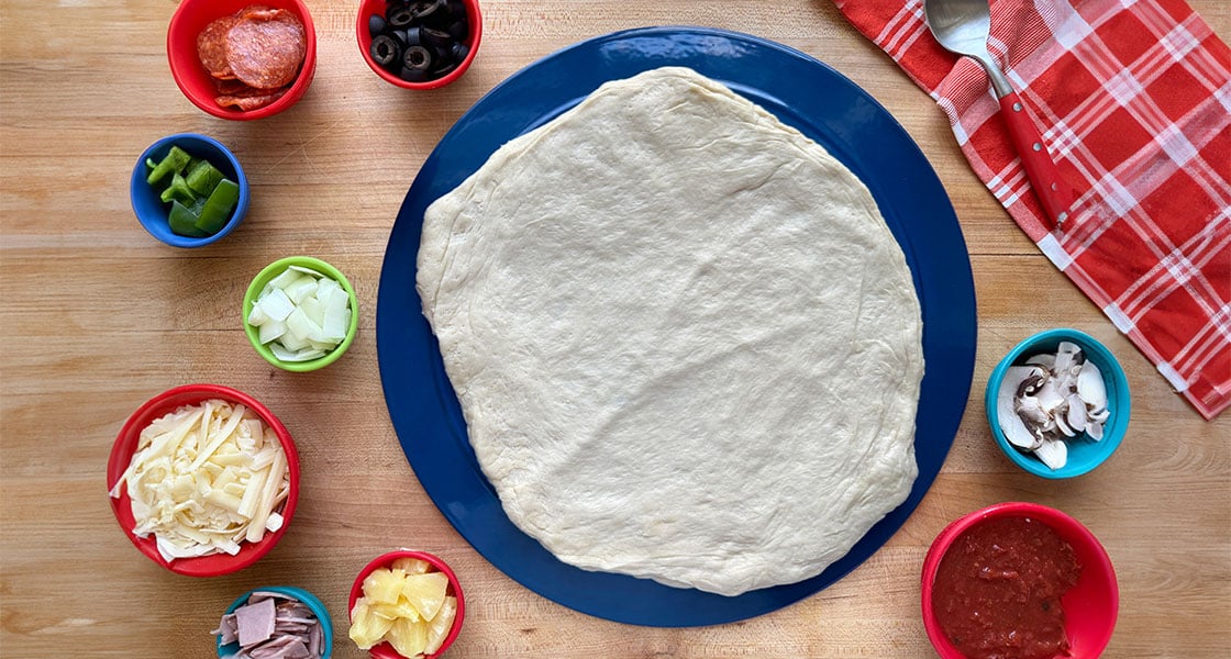 pizza dough surrounded by toppings