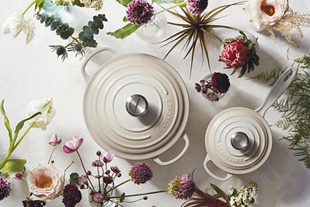 overhead shot of cream colored dutch ovens surrounded by flowers