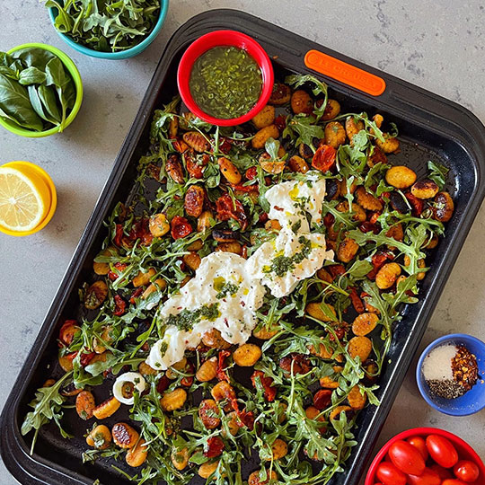 gnochhi and arugula on a sheet pan with burrata