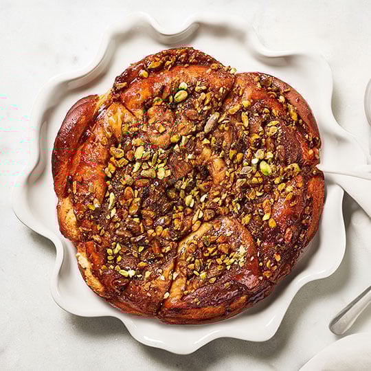sticky buns topped with nuts on a platter with ruffled edges