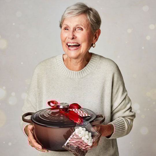 excited woman holds ganache brown dutch oven and cocoa mix