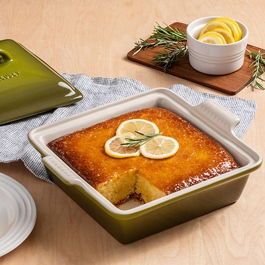 cake topped with lemon slices in a square stoneware baker