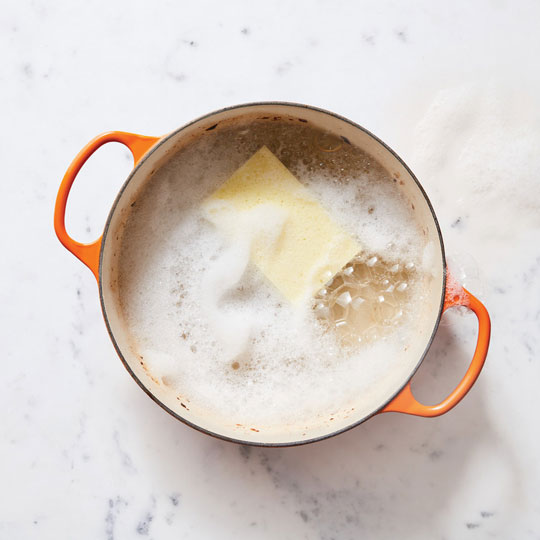 dutch oven filled with soapy water and a sponge