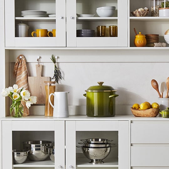 cabinets and counters filled with white, yellow and green kitchenware
