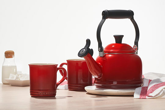cerise red tea kettle beside two red mugs