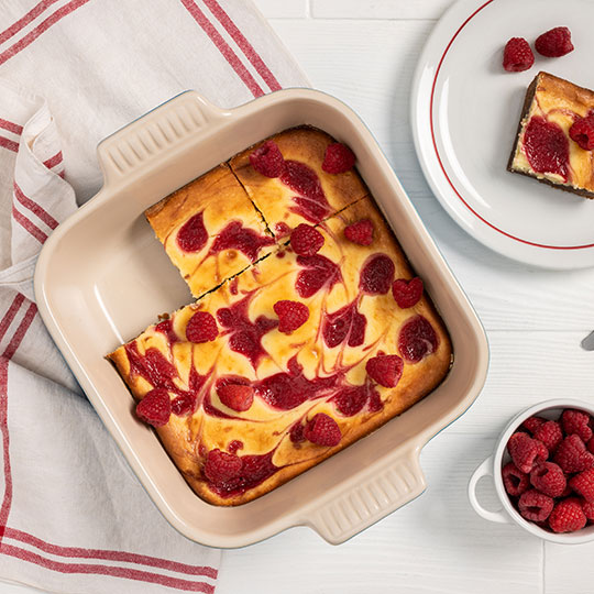 raspberry cheesecake brownies baked in a square stoneware baker