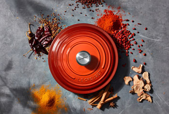 cayenne colored lid surrounded by ground, chopped and whole spices