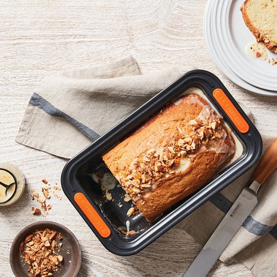non-stick loaf pan with sliced pound cake topped with nuts