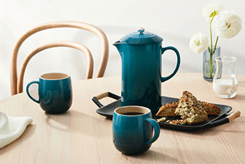 french press in deep teal alongside deep teal tea mugs