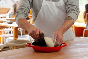 a person works with dough in a Le Creuset bread oven
