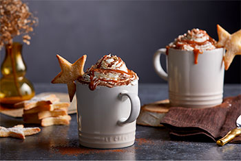 hot cocoa adorned with whipped cream and a star cookie