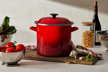 red stockpot surrounded by ingredients for making pasta