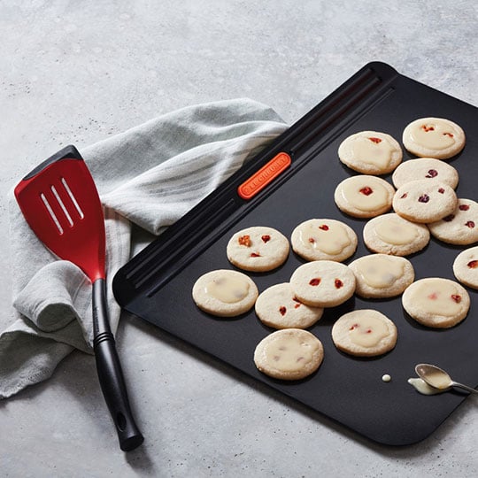 red and black bi-material spatula next to a sheet pan of cookies