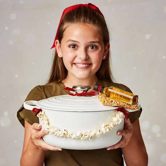 young woman holds a dutch oven wrapped in a popcorn string