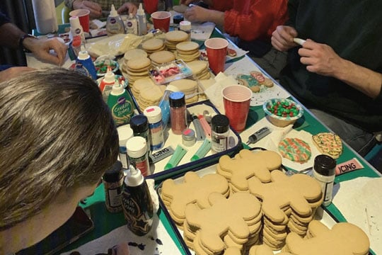 people decorating cookies around a table