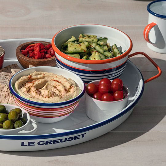 bowl of hummus surrounded by veggies sliced for dipping