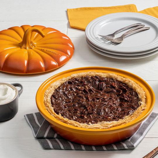 pecan pie in a pie dish with a pumpkin shaped lid