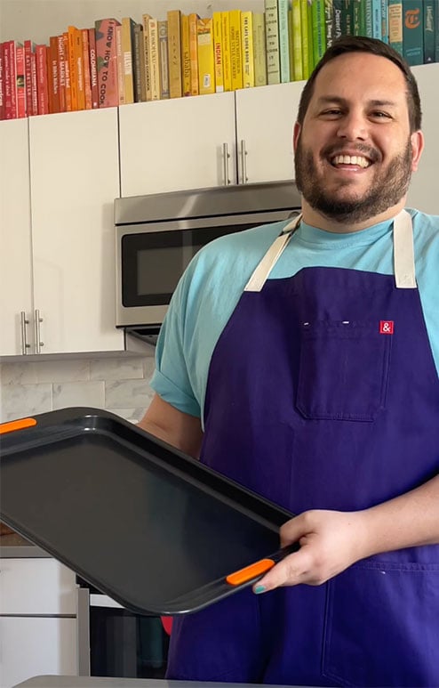 Dan Pelosi in a kitchen holding a le creuset non-stick sheet pan