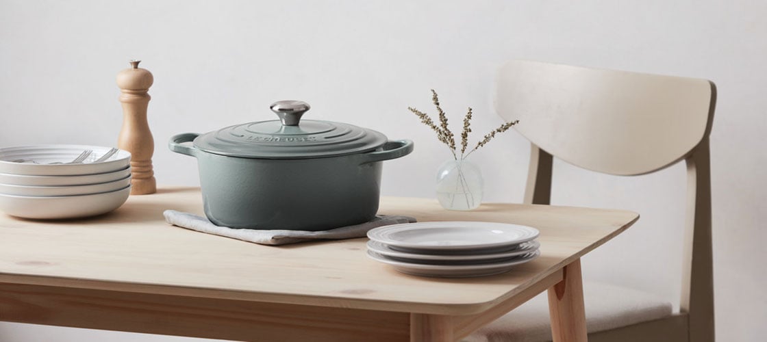 sea salt dutch oven on a table with plates, silverware and a pepper mill