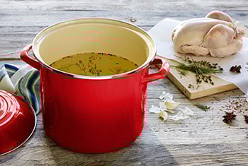 red stockpot and ingredients for fresh chicken stock