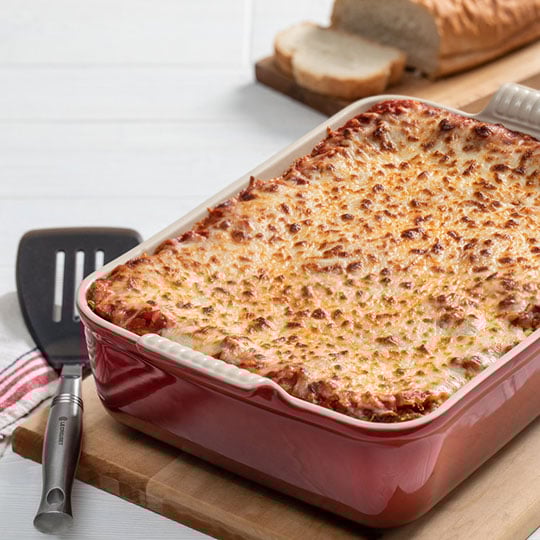 lasagna in a red stoneware baker