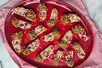 a plate of biscotti dipped in chocolate with pistachio pieces
