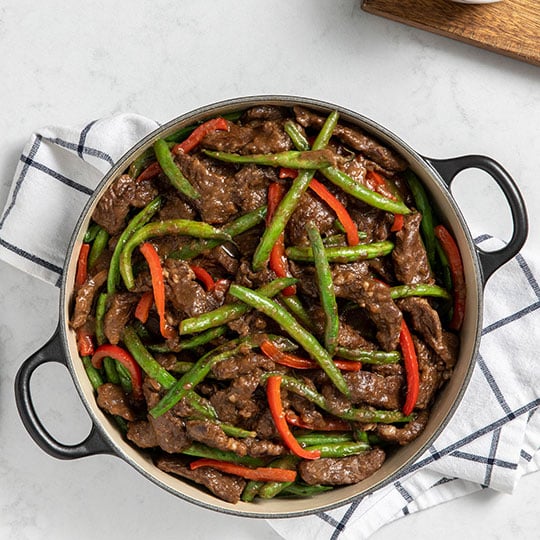 overhead shot of beef and green bean stir-fry in a Dutch oven