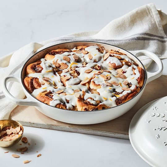 icing topped cinnamon rolls in a cast iron braiser