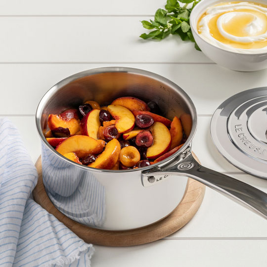 stainless saucepan filled with peach slices and cherries