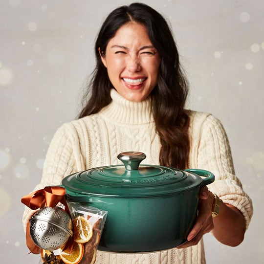 excited woman holds artichaut green dutch oven