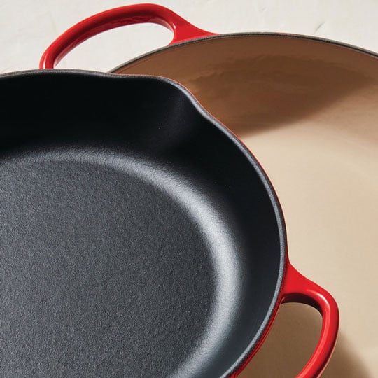 skillet with rough black enamel juxtaposed with a braiser coated in smooth sand-colored enamel