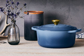 chambray light blue dutch oven on counter next to stem of flowers