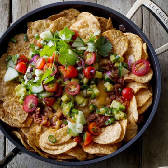 nachos in a non-stick briaser with  meat, cheese, lots of fresh veggies and jalapeños
